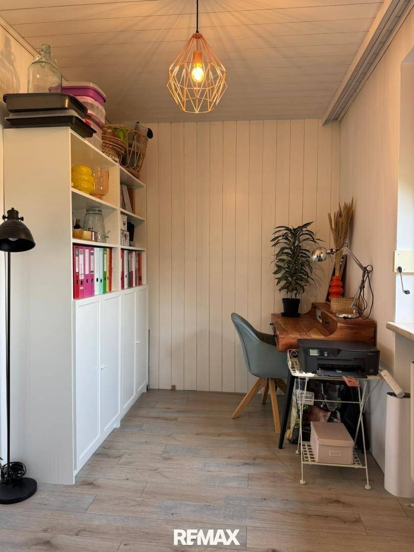 Helles Arbeitszimmer mit Holzvertäfelung, Schreibtisch und Bücherregal.