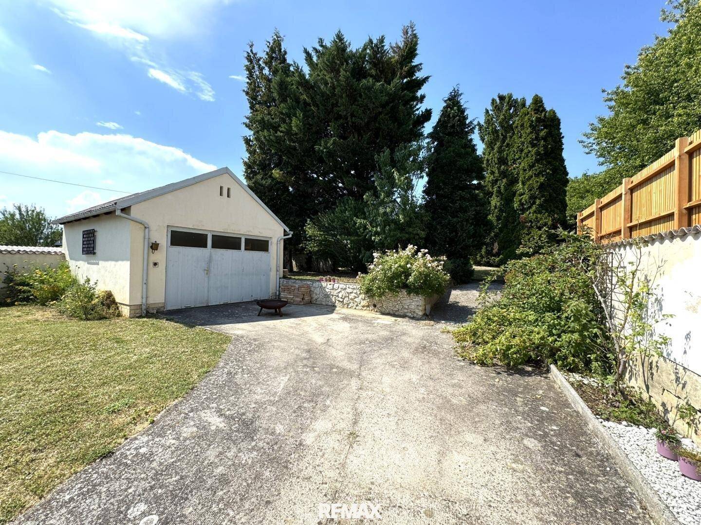 Freistehende Garage mit großzügiger Zufahrt und umgebender Grünfläche.