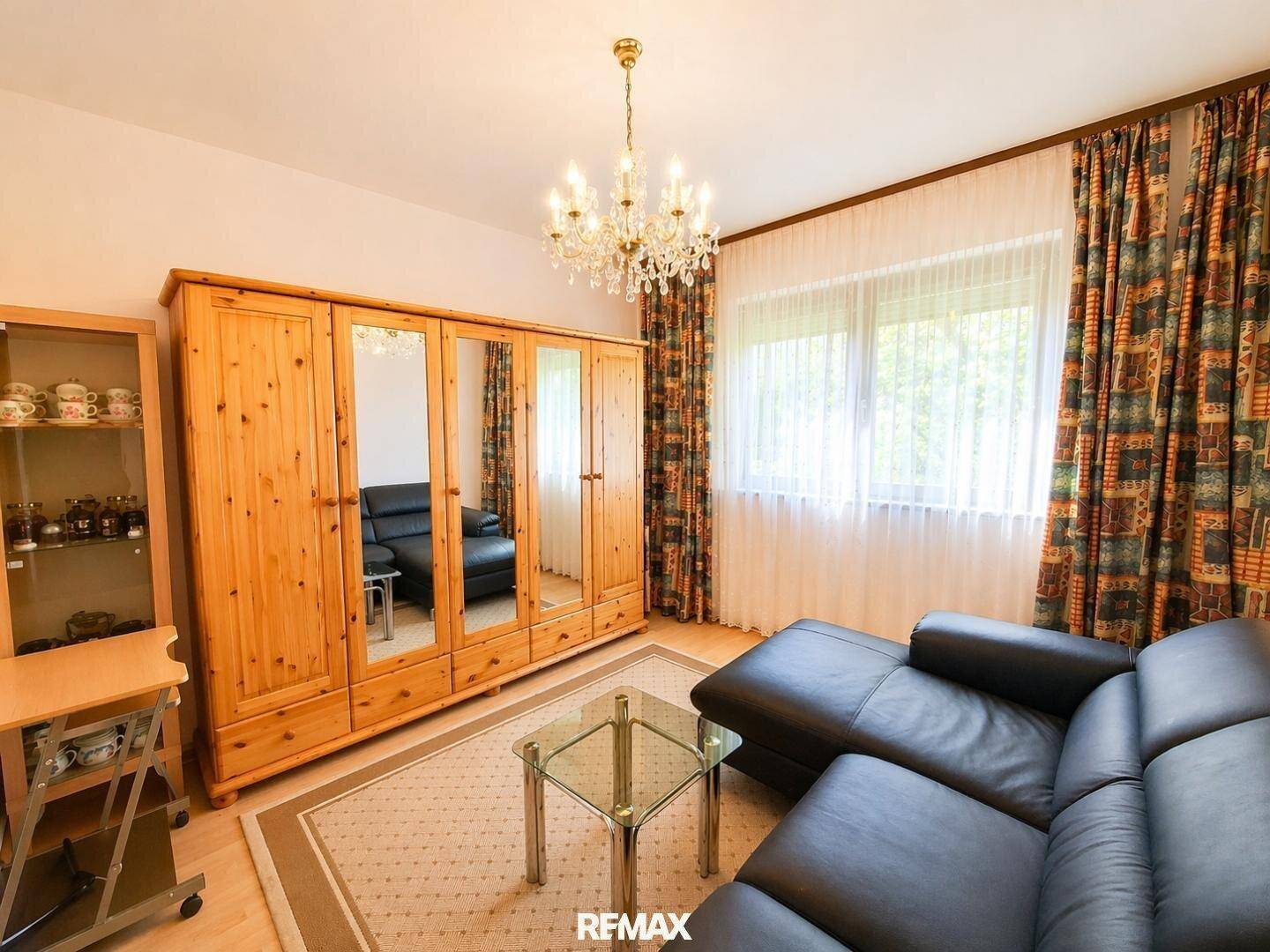 Gemütliches Schlafzimmer mit einem großen Holzkleiderschrank, Ledersofa und Teppich.