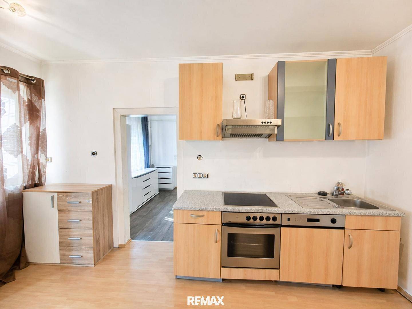 Funktionale kleine Küchenzeile mit Kochfeld, Backofen und praktischen Hängeschränken.