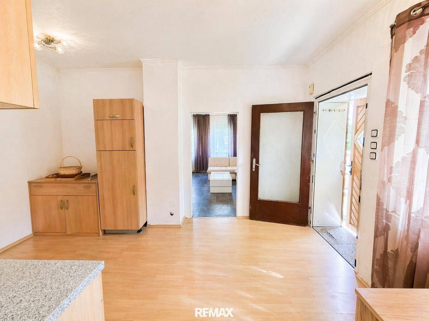Eingangsbereich oder kleiner Wohnraum mit Laminatboden und Zugang zum Freien.