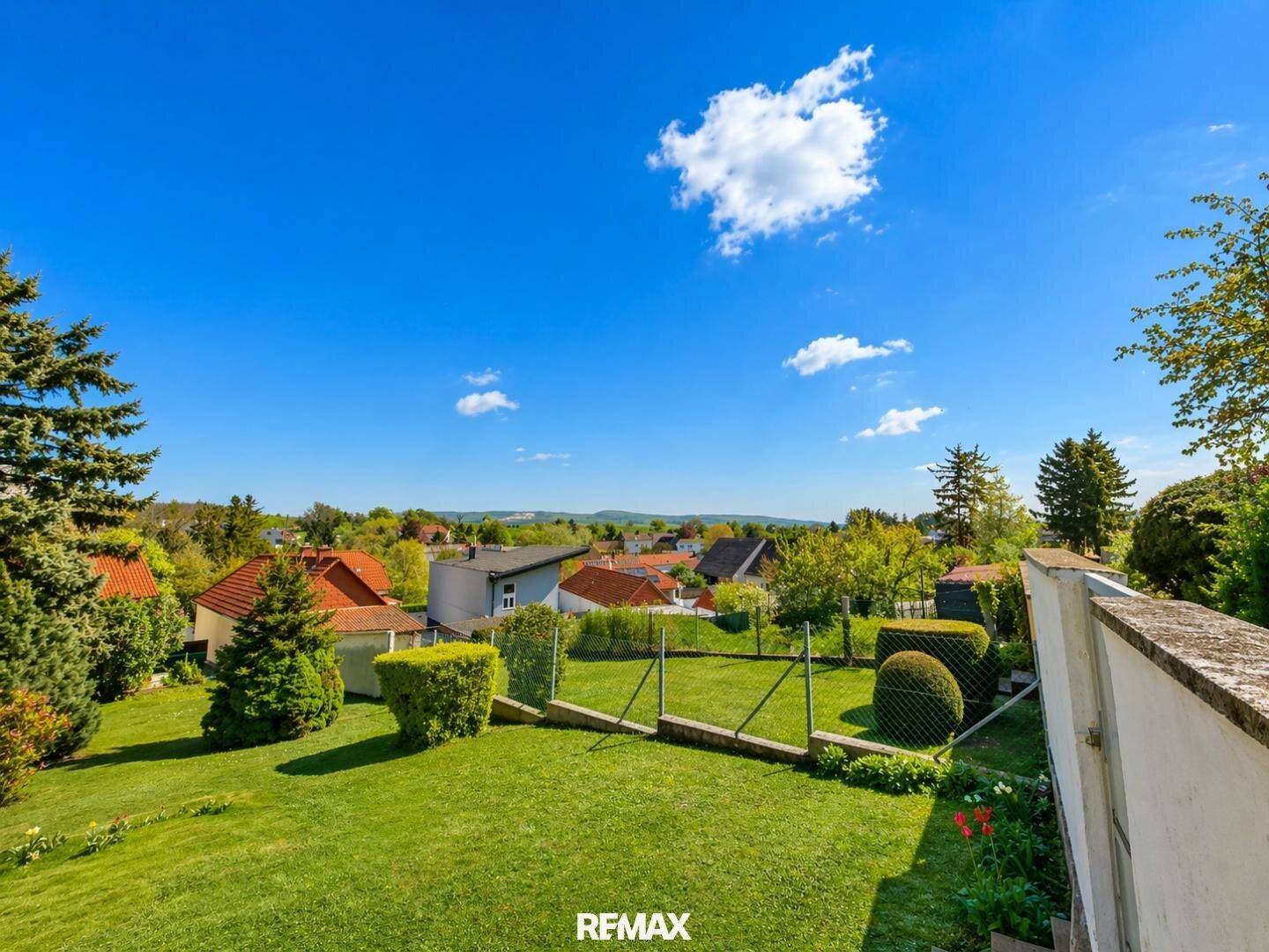 Weitläufiger Garten mit gepflegtem Rasen und Blick auf die umliegende Wohnsiedlung.