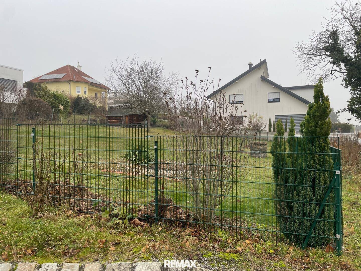 Weitläufiges Grundstück mit Rasenfläche, umgeben von weiteren Wohnhäusern und Bäumen.