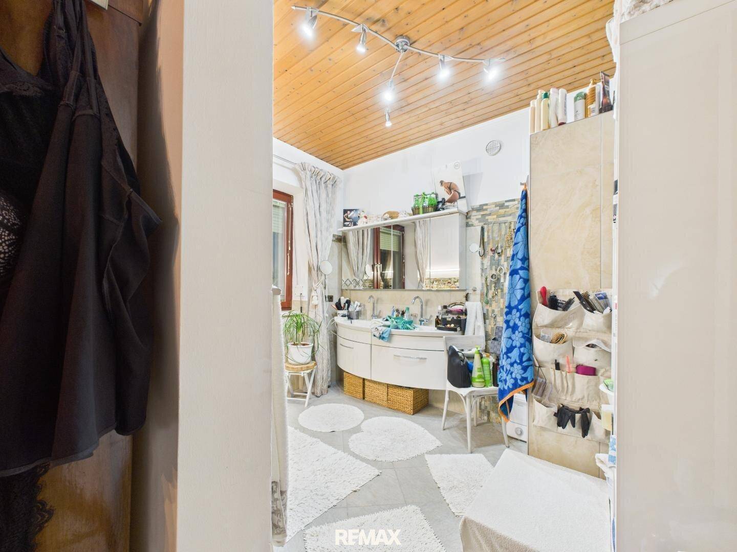 Geräumiges Badezimmer mit Doppelwaschbecken, Holzdecke und praktischen Ablagemöglichkeiten.
