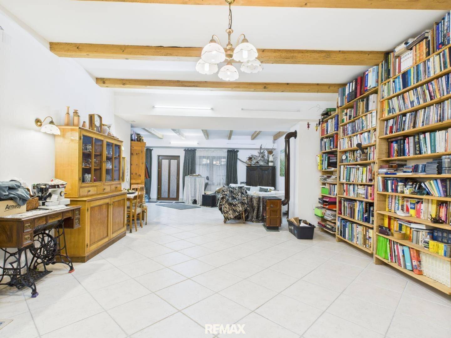 Offener Wohnbereich mit Bibliothek, Essbereich und Holzbalken an der Decke.