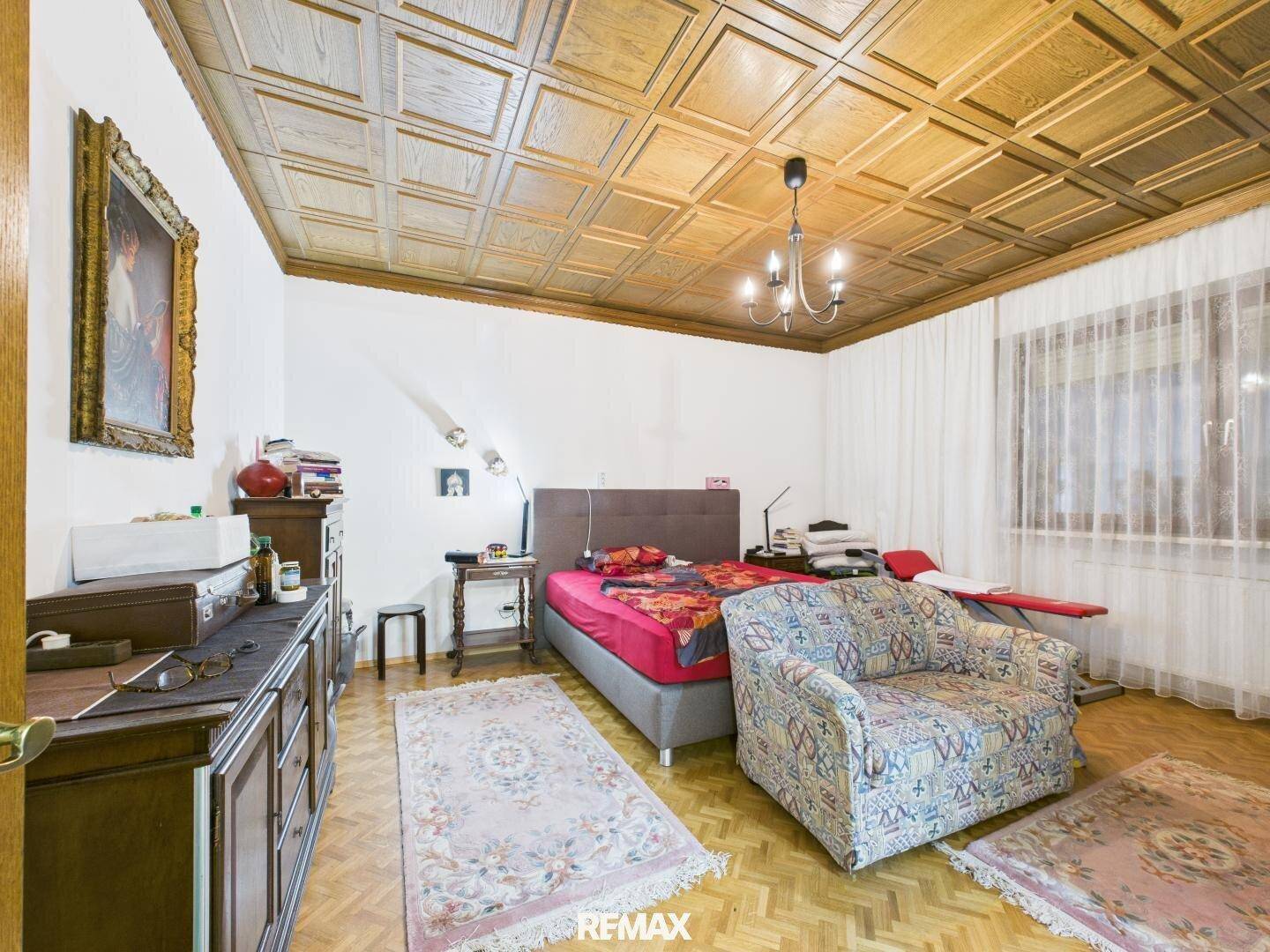 Gemütliches Schlafzimmer mit Holzkassettendecke, Parkettboden und traditioneller Einrichtung.