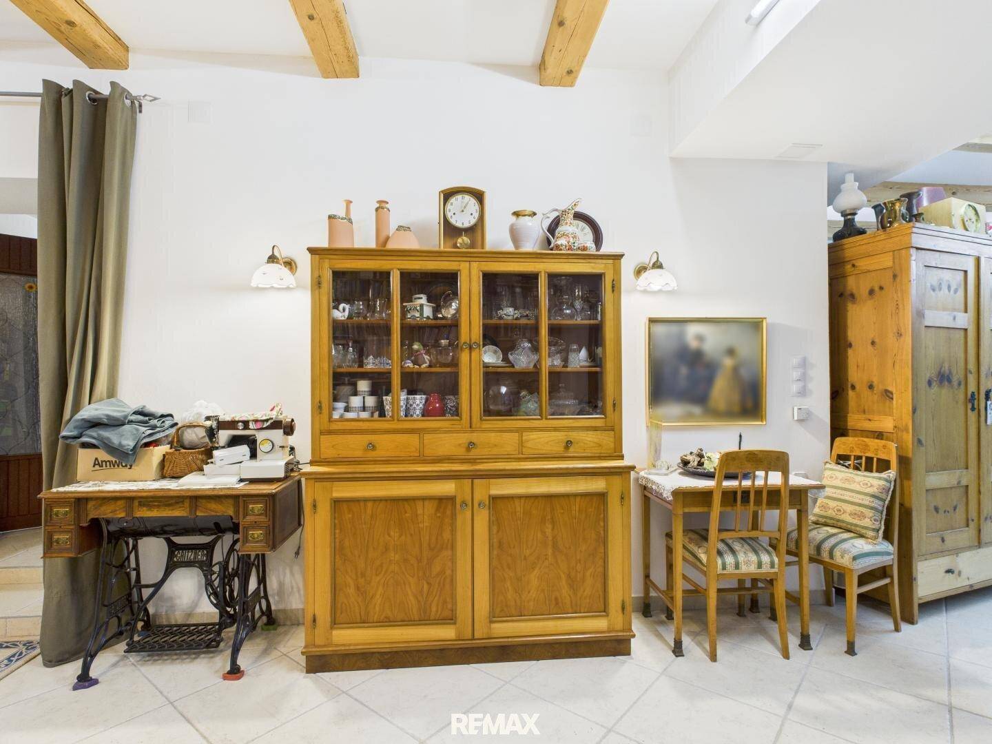 Essbereich mit traditionellem Holzschrank, Esstisch und Nähmaschine als dekoratives Element.