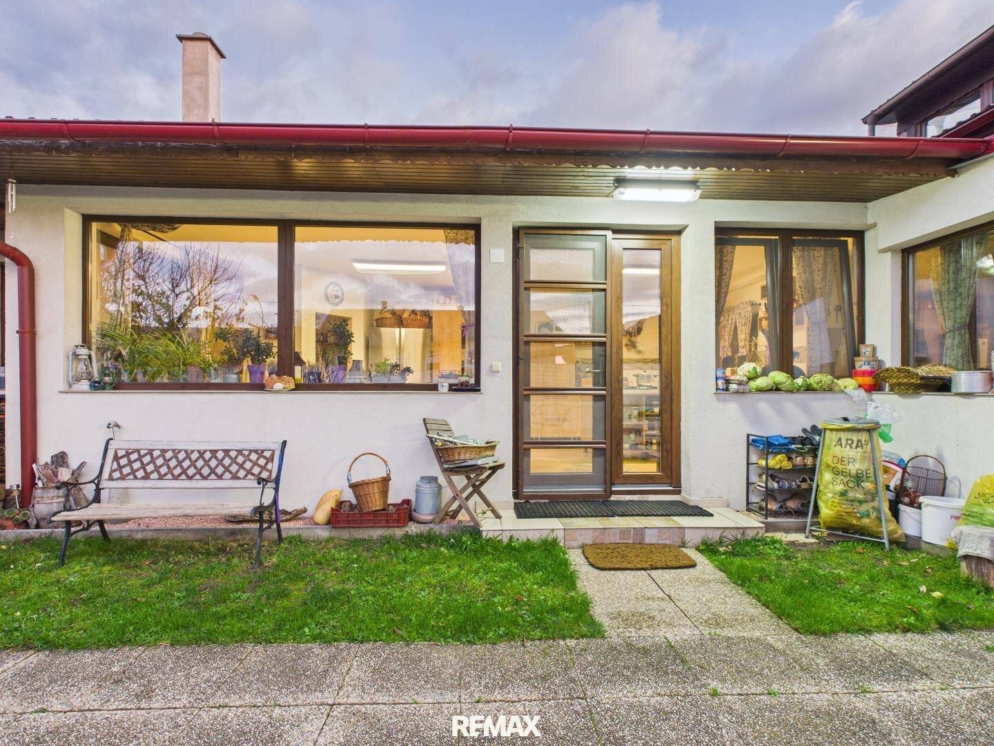 Eingangsbereich des Hauses mit großer Fensterfront, kleiner Rasenfläche und gepflastertem Weg.