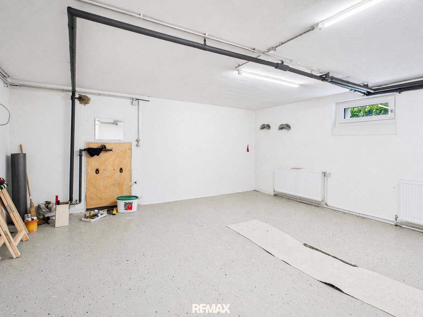 Geräumige Garage mit Betonboden und ausreichend Platz für Fahrzeuge und Lagerung.