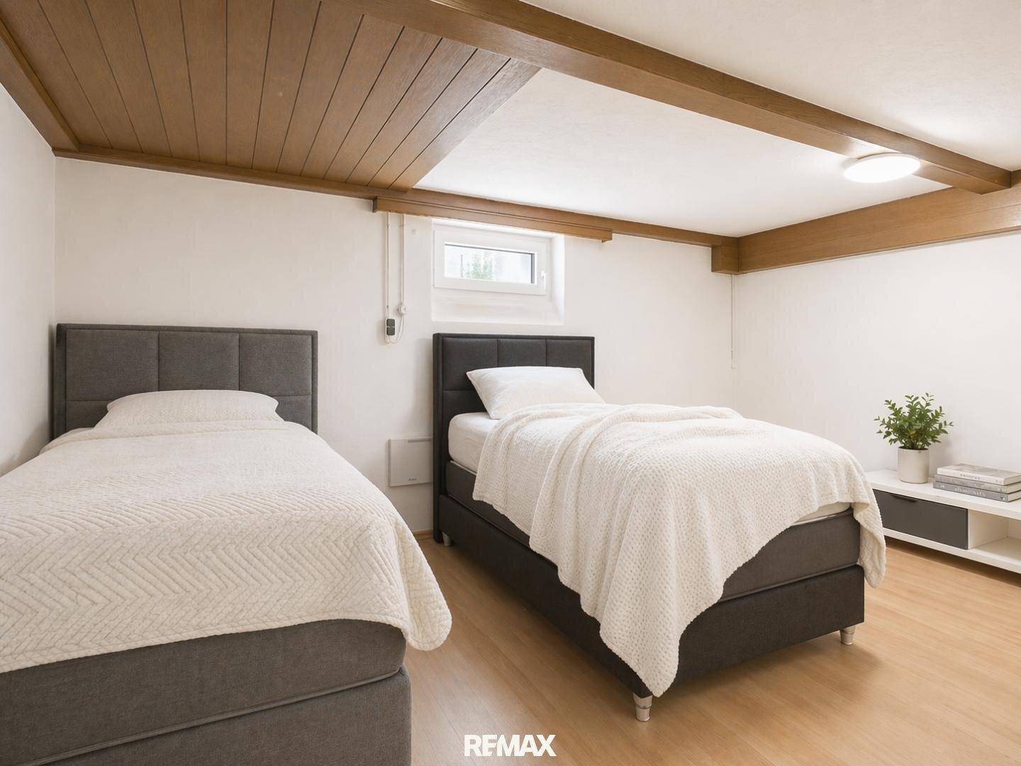 Schlafzimmer im Untergeschoss mit zwei Einzelbetten und Holzbalkendecke.