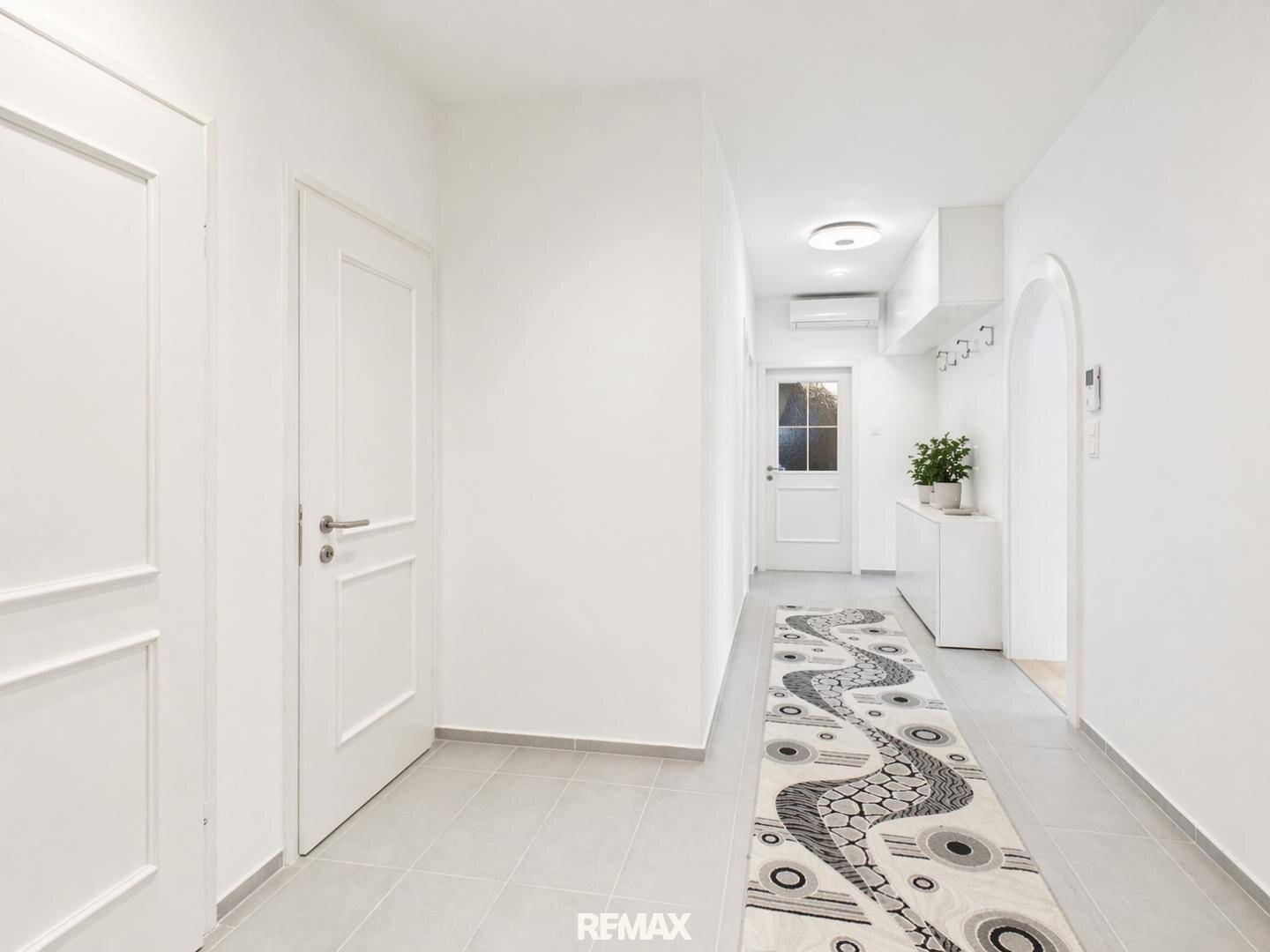 Heller Flur mit Fliesenboden, Garderobe und Zugang zu verschiedenen Räumen.