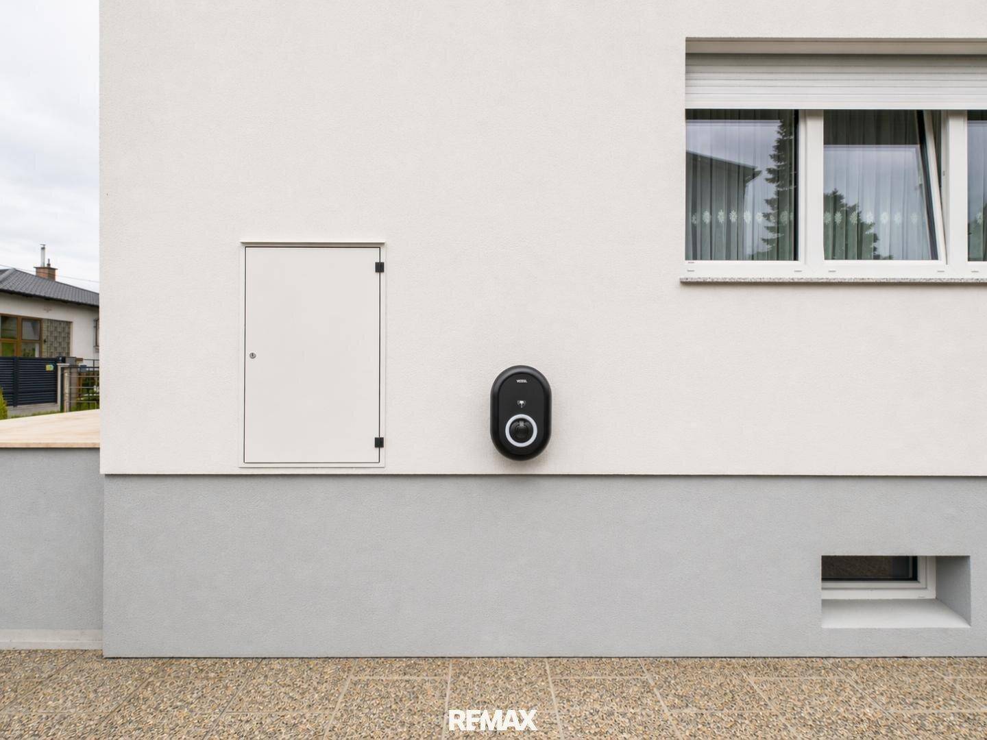 Außenwand des Hauses mit einer Ladestation für Elektrofahrzeuge und einem Fenster.