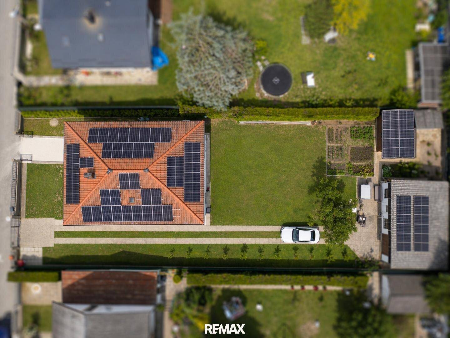 Luftaufnahme des Hauses mit großem Garten, Zufahrt und zahlreichen Solarmodulen auf dem Ziegeldach.