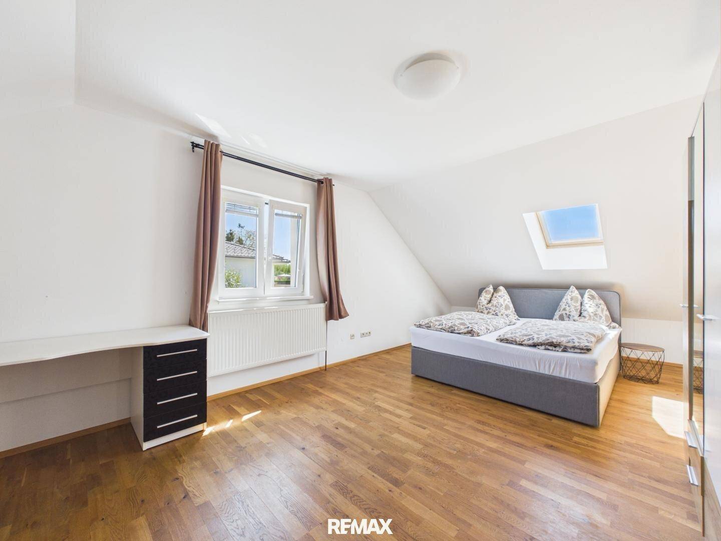 Gemütliches Schlafzimmer im Dachgeschoss mit Holzboden, Bett und Dachfenster für viel Licht.