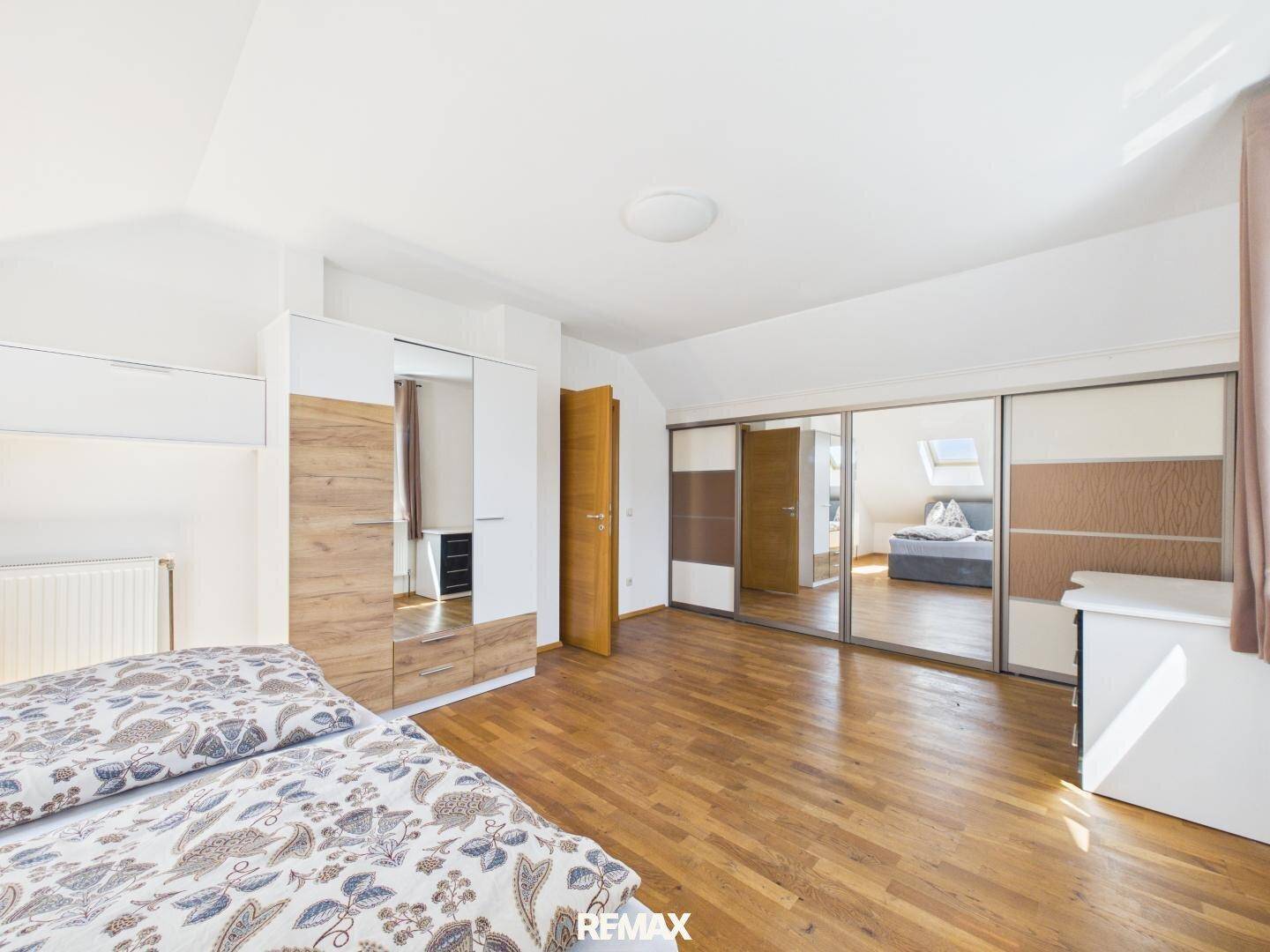 Geräumiges Schlafzimmer im Dachgeschoss mit Holzboden und großen Spiegelschränken.