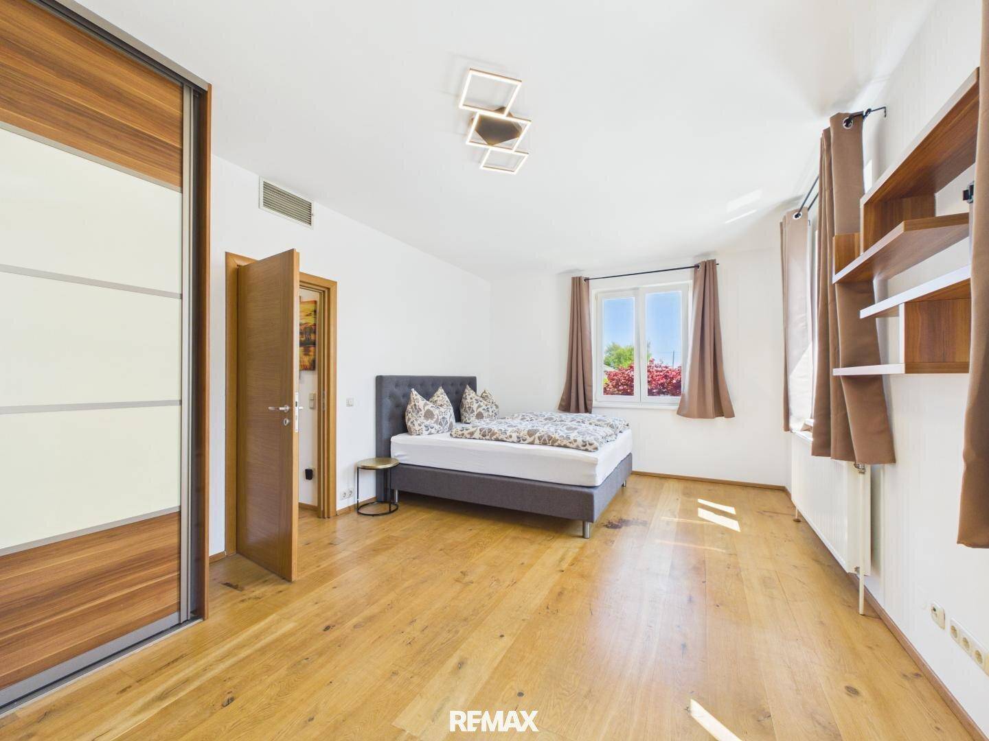 Helles Schlafzimmer mit Holzboden, Doppelbett und großem Einbauschrank.