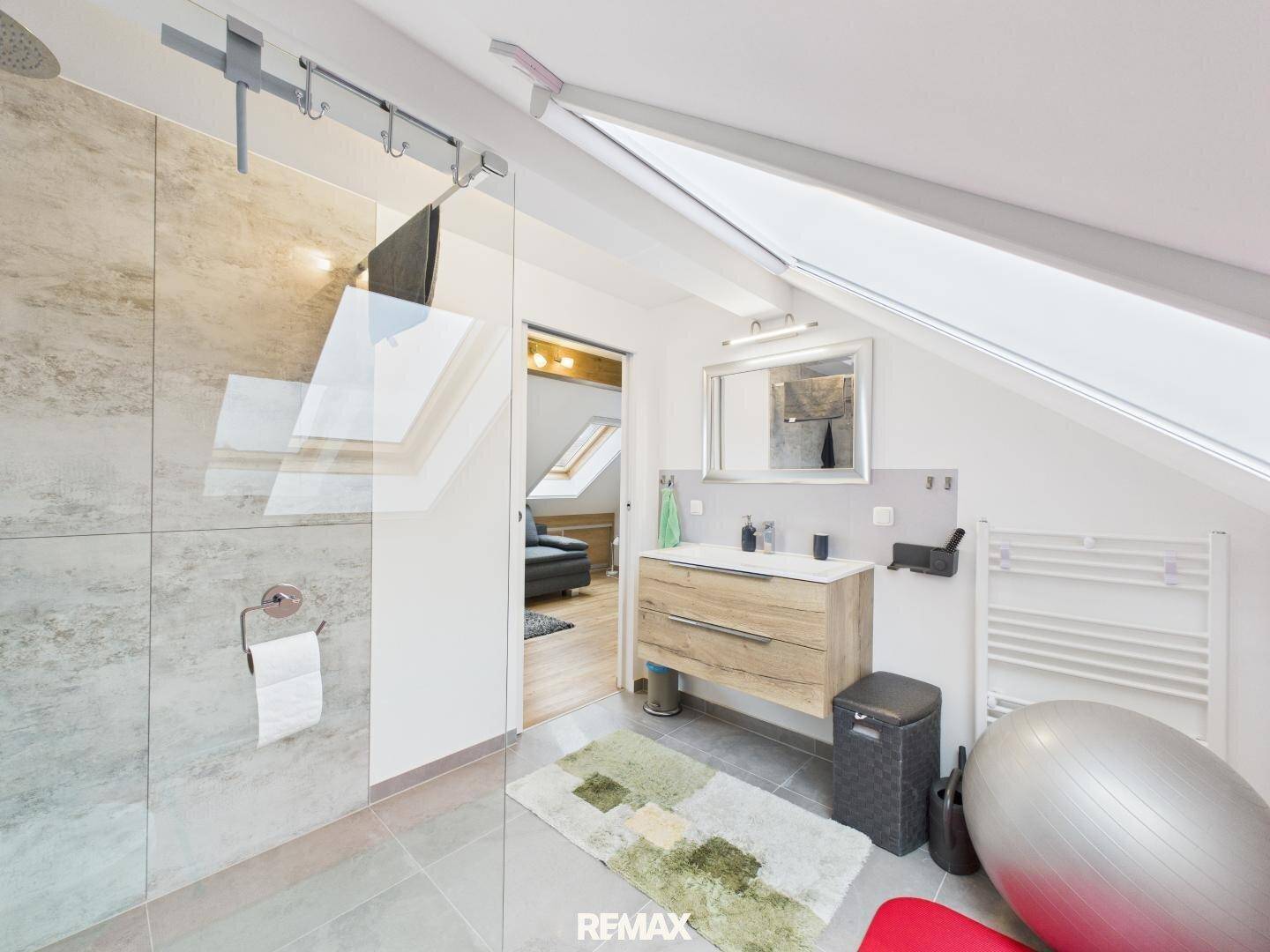 Modernes Badezimmer im Dachgeschoss mit ebenerdiger Dusche, Waschtisch und Dachfenster.