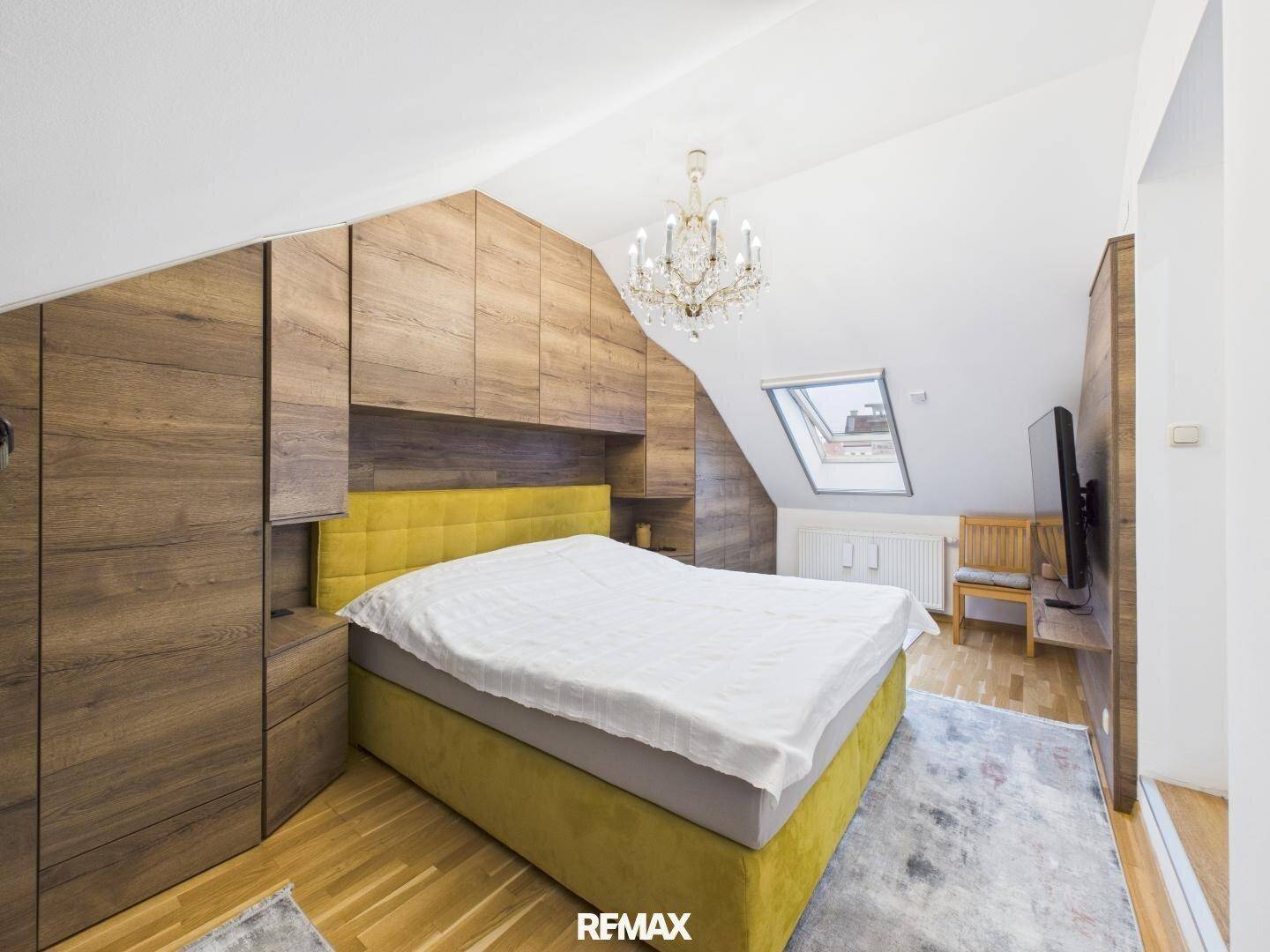 Gemütliches Schlafzimmer im Dachgeschoss mit Holzeinbauschränken und Dachfenster.