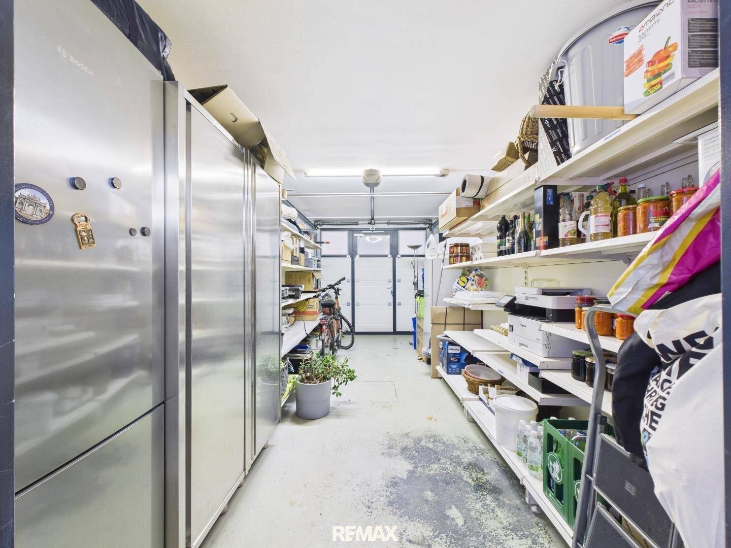 Geräumige Garage oder Abstellraum mit Regalen, Fahrrädern und großem Kühlschrank.