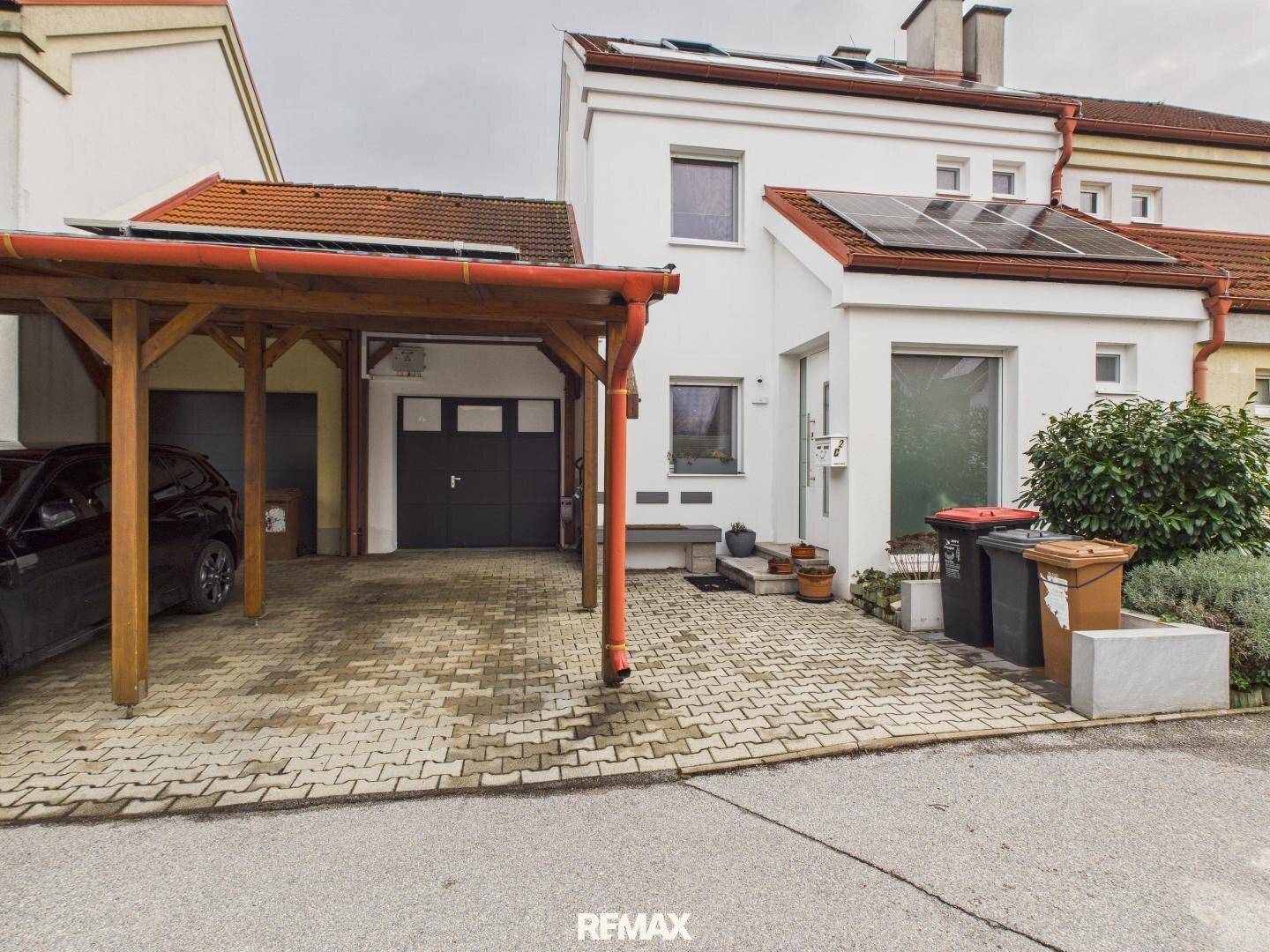 Außenansicht des Hauses mit Carport, Garage und Photovoltaikanlage auf dem Dach.