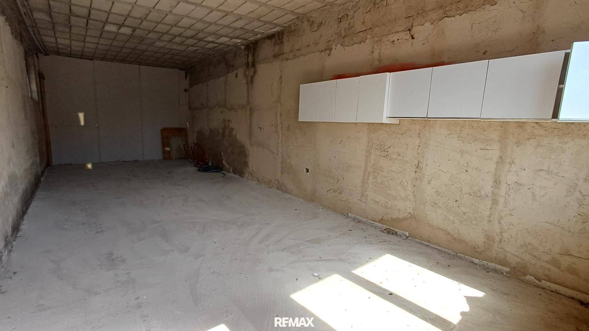 Großer, leerer Raum im Rohbau mit Betonboden und sichtbaren Deckenstrukturen.