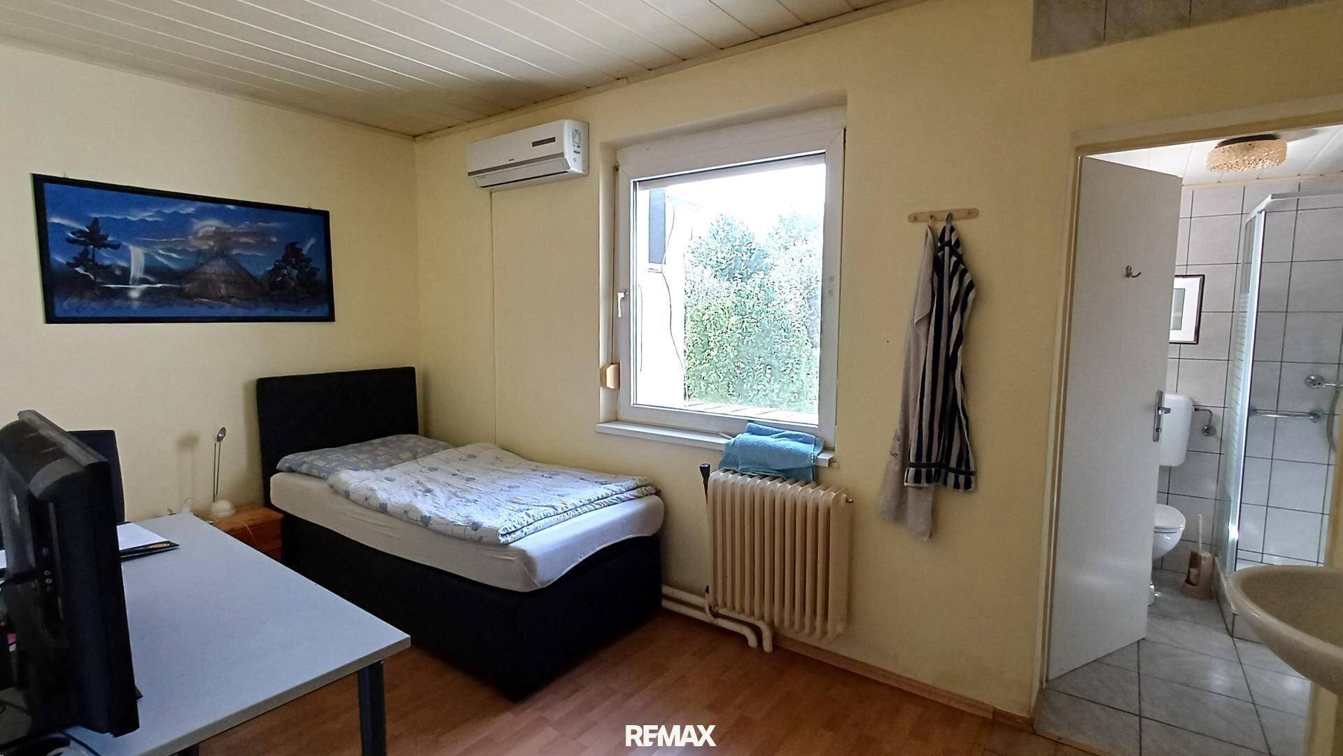 Schlafzimmer mit Einzelbett, Klimaanlage und direktem Zugang zu einem Badezimmer.