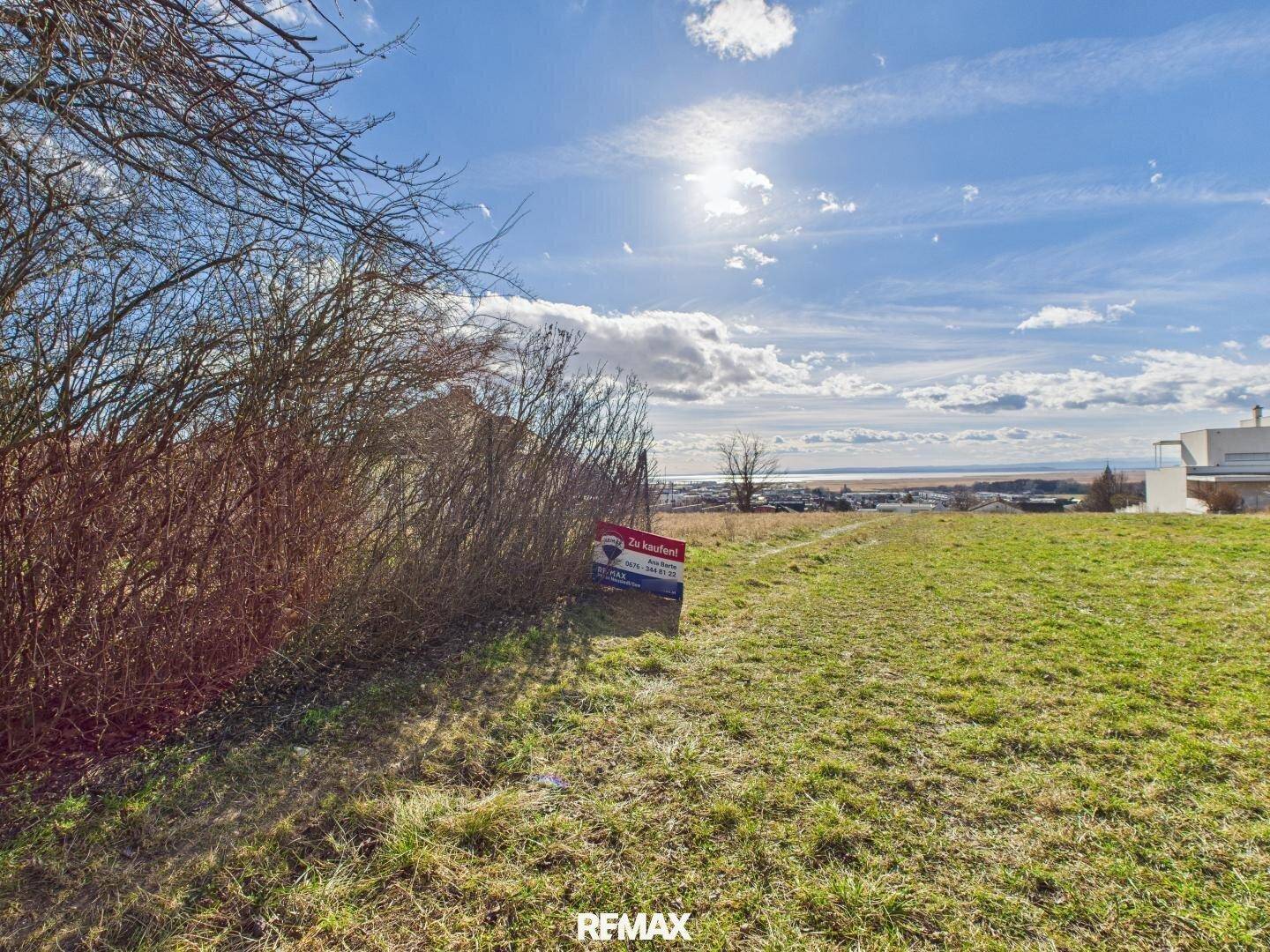 Sonniges Grundstück mit natürlicher Vegetation und Fernblick auf das Wasser und die Landschaft.