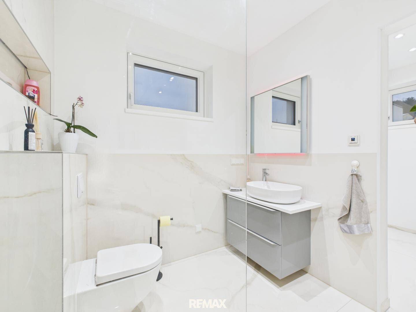 Modernes Badezimmer mit wandhängendem WC, Einzelwaschbecken und Marmorfliesen.