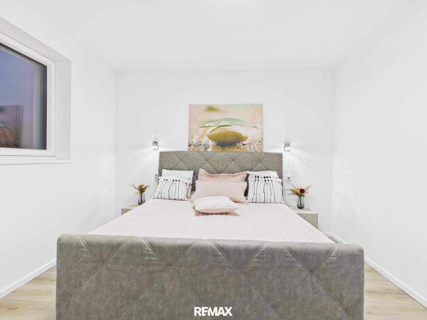 Gemütliches Schlafzimmer mit gepolstertem Bett, Nachttischen und dekorativem Wandbild.