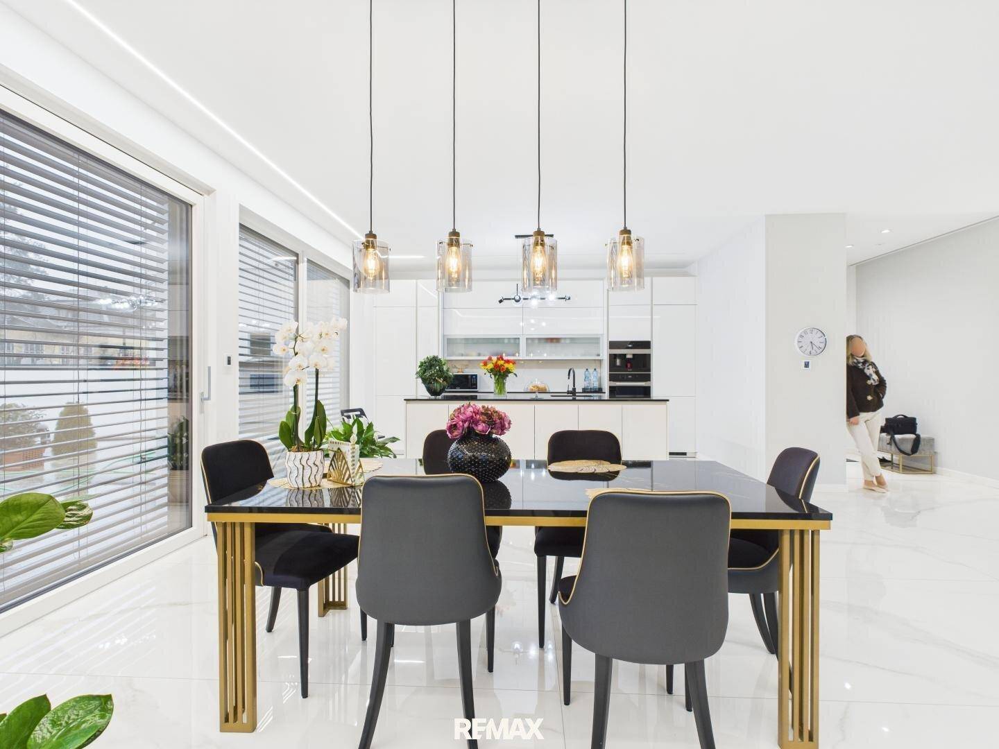 Eleganter Essbereich mit schwarzem Tisch, modernen Pendelleuchten und Blick auf die offene Küche.