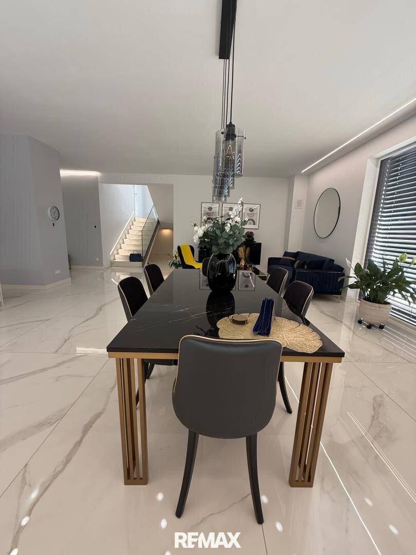 Moderner Essbereich mit elegantem schwarzen Tisch und Blick auf den stilvoll eingerichteten Wohnbereich.