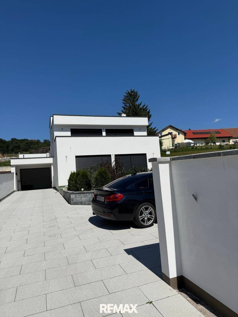 Moderne Villa mit breiter Auffahrt, integrierter Garage und gepflegter Außenanlage.