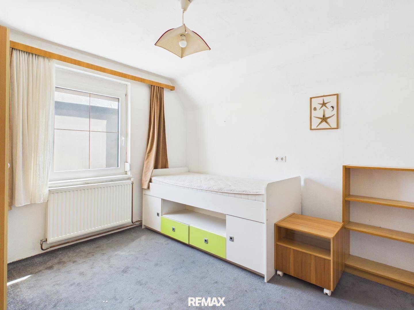 Kinderzimmer mit Einzelbett, integriertem Stauraum und grauem Teppichboden.