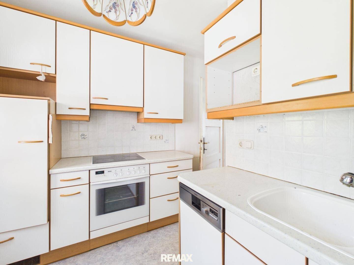 Funktionale Küche mit weißen Schränken, Holzdetails und integrierten Geräten.