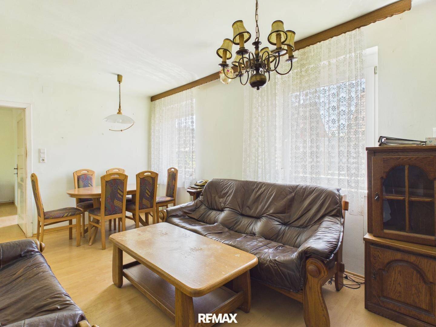 Geräumiger Wohn- und Essbereich mit traditionellen Möbeln, Ledersofa und Kronleuchter.