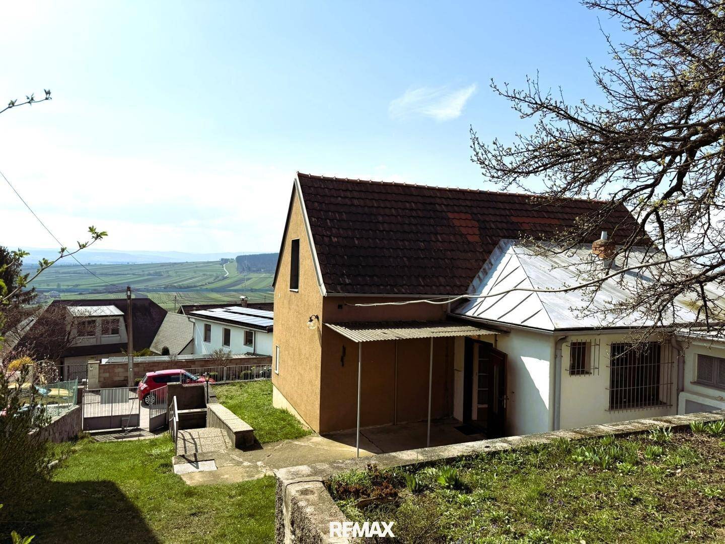 Seitenansicht des Hauses mit überdachtem Eingangsbereich und weitem Blick über die Landschaft.