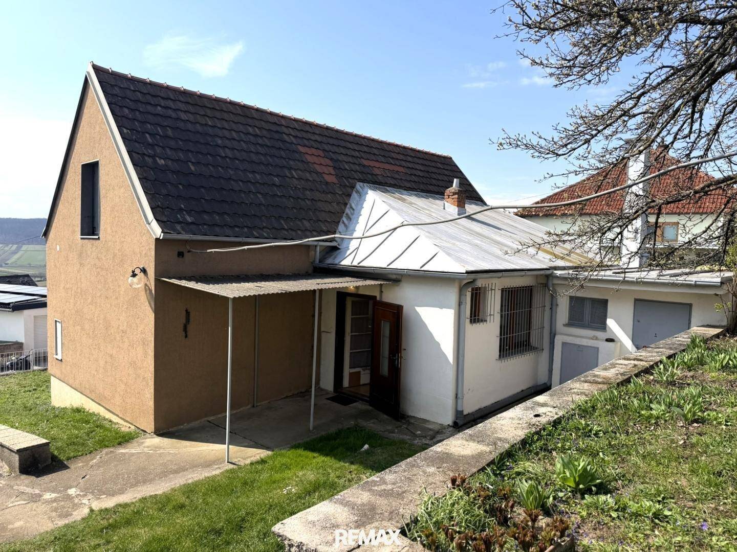 Seitenansicht des Hauses mit überdachtem Eingang und Zugang zu weiteren Räumen im Untergeschoss.