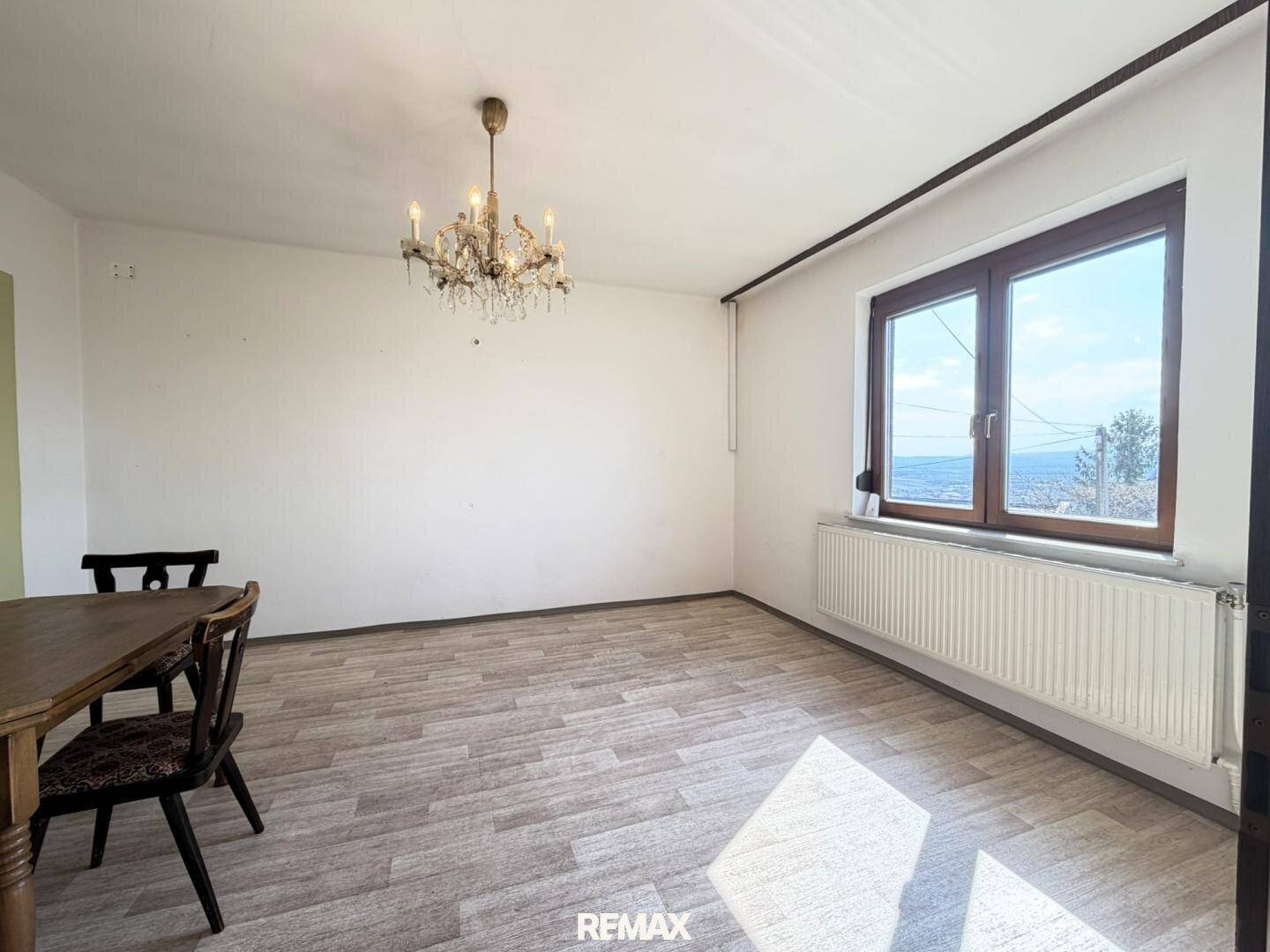 Heller Wohn-Essbereich mit Holzboden und Kronleuchter, bietet weiten Blick nach draußen.
