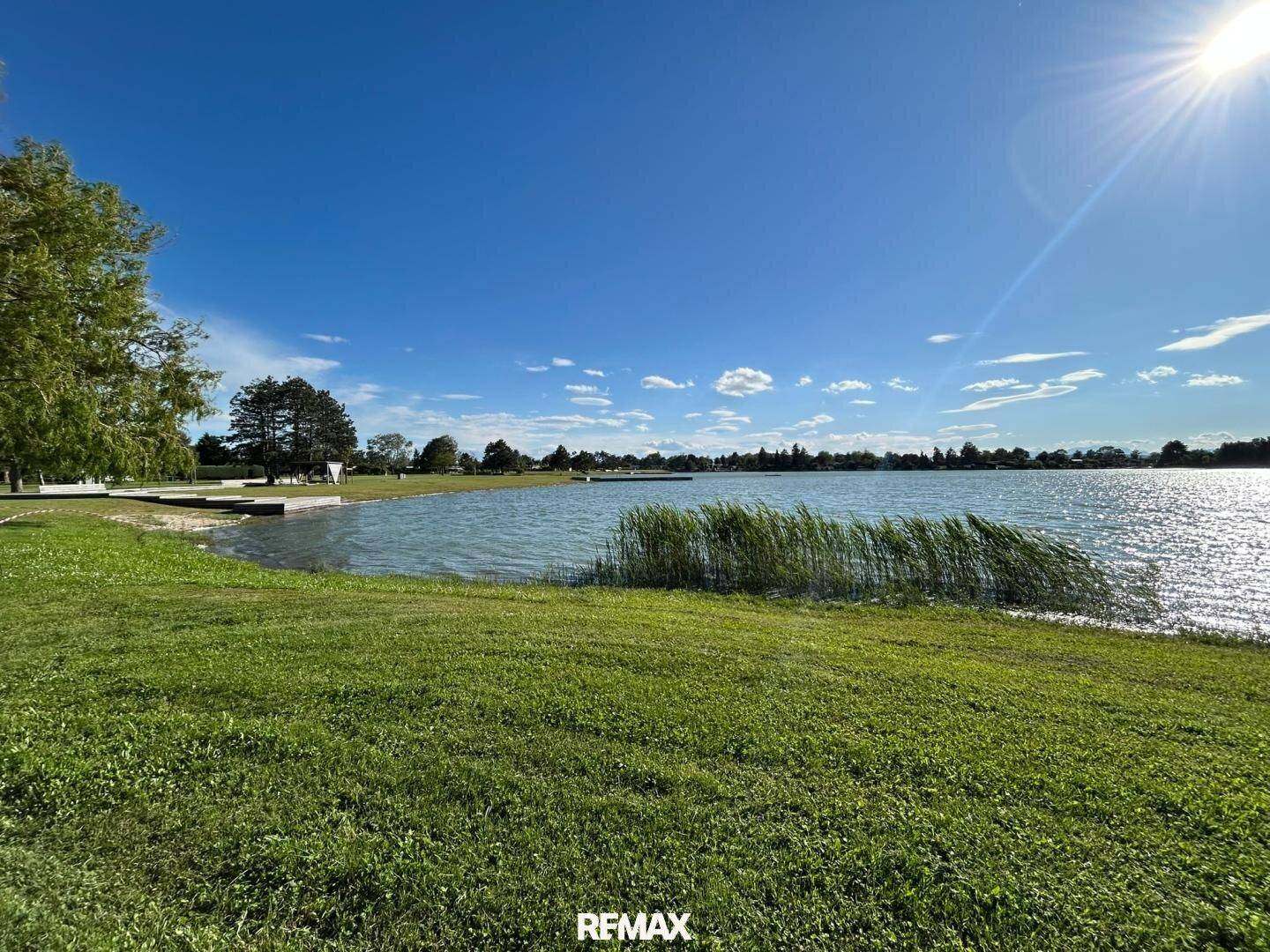 Sonniger Tag am See mit weitem Blick über das Wasser und grüne Uferlandschaft.