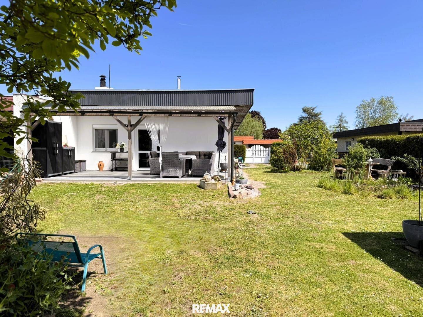 Weitläufiger Garten mit überdachter Terrasse und Sitzgelegenheiten hinter dem Einfamilienhaus.