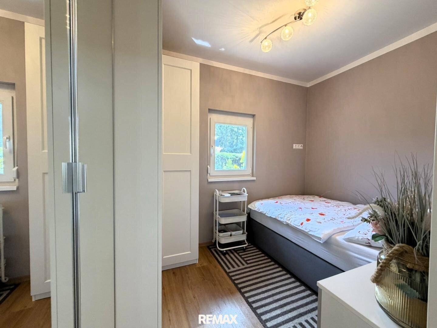 Gemütliches Schlafzimmer mit Einzelbett, Einbauschrank und Fenster zum Garten.