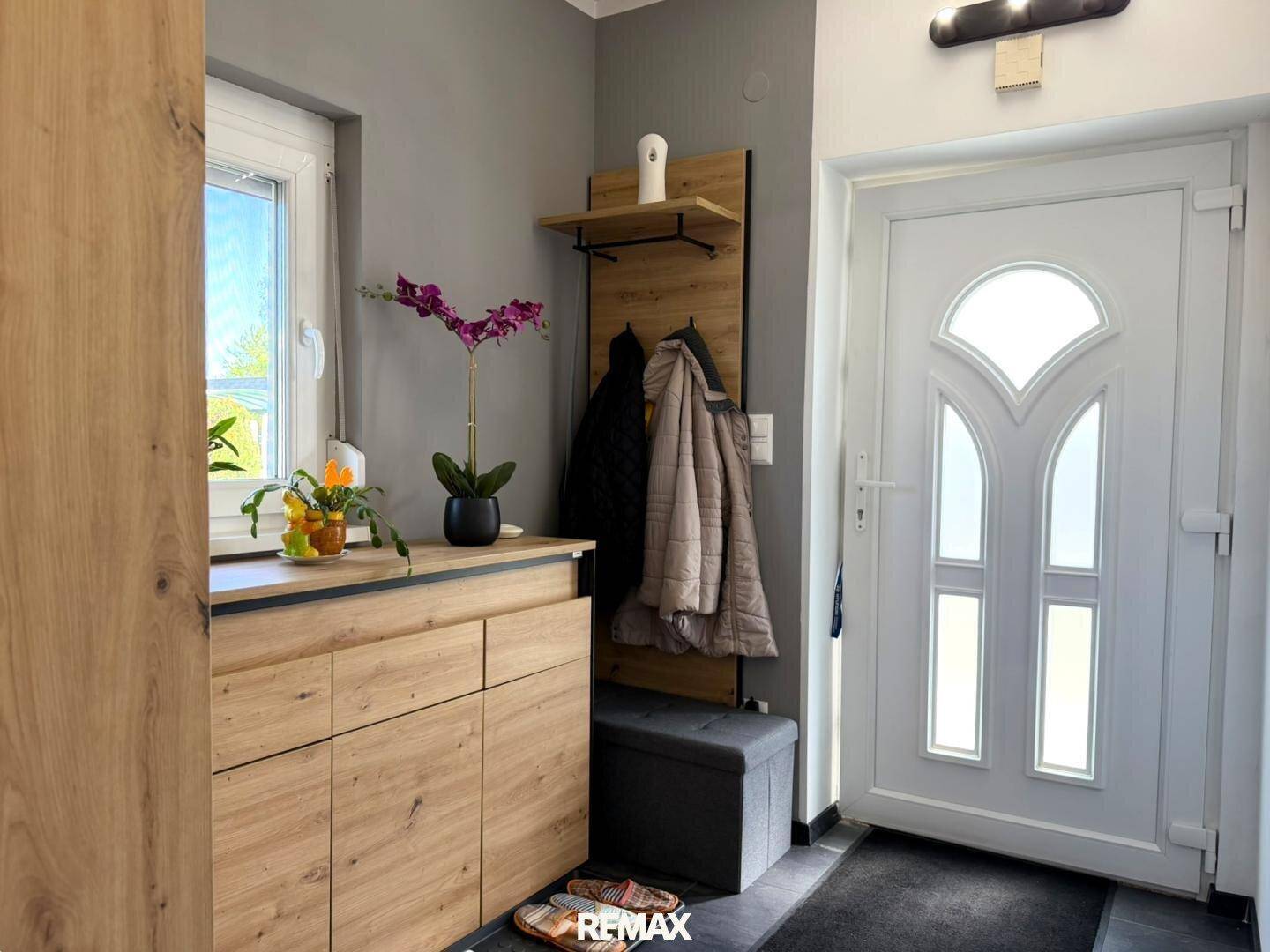Heller Eingangsbereich mit Garderobe, Schuhschrank und weißer Eingangstür.