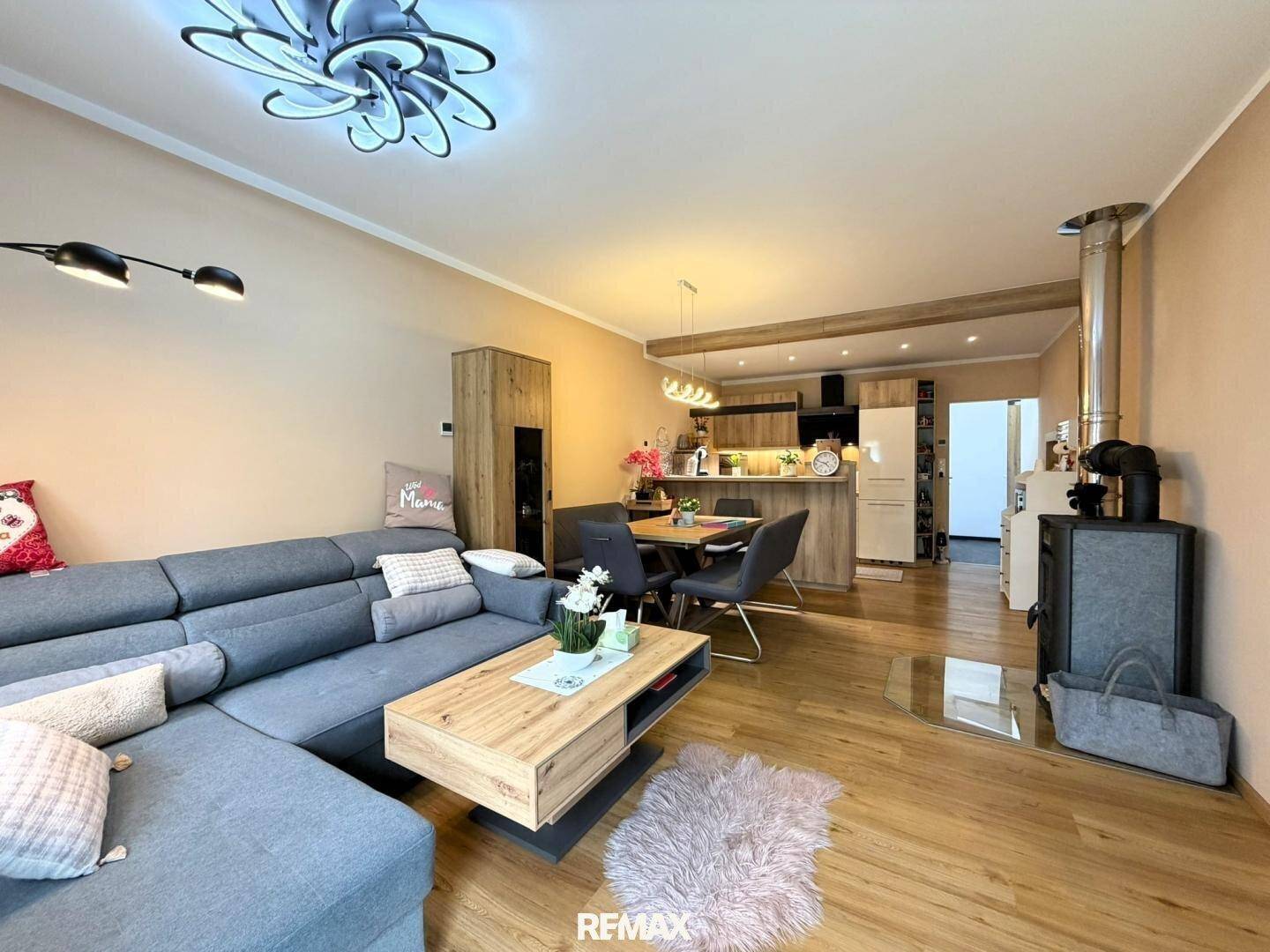Gemütlicher Wohnbereich mit großem Sofa, Holzboden und Kaminofen in offener Gestaltung.