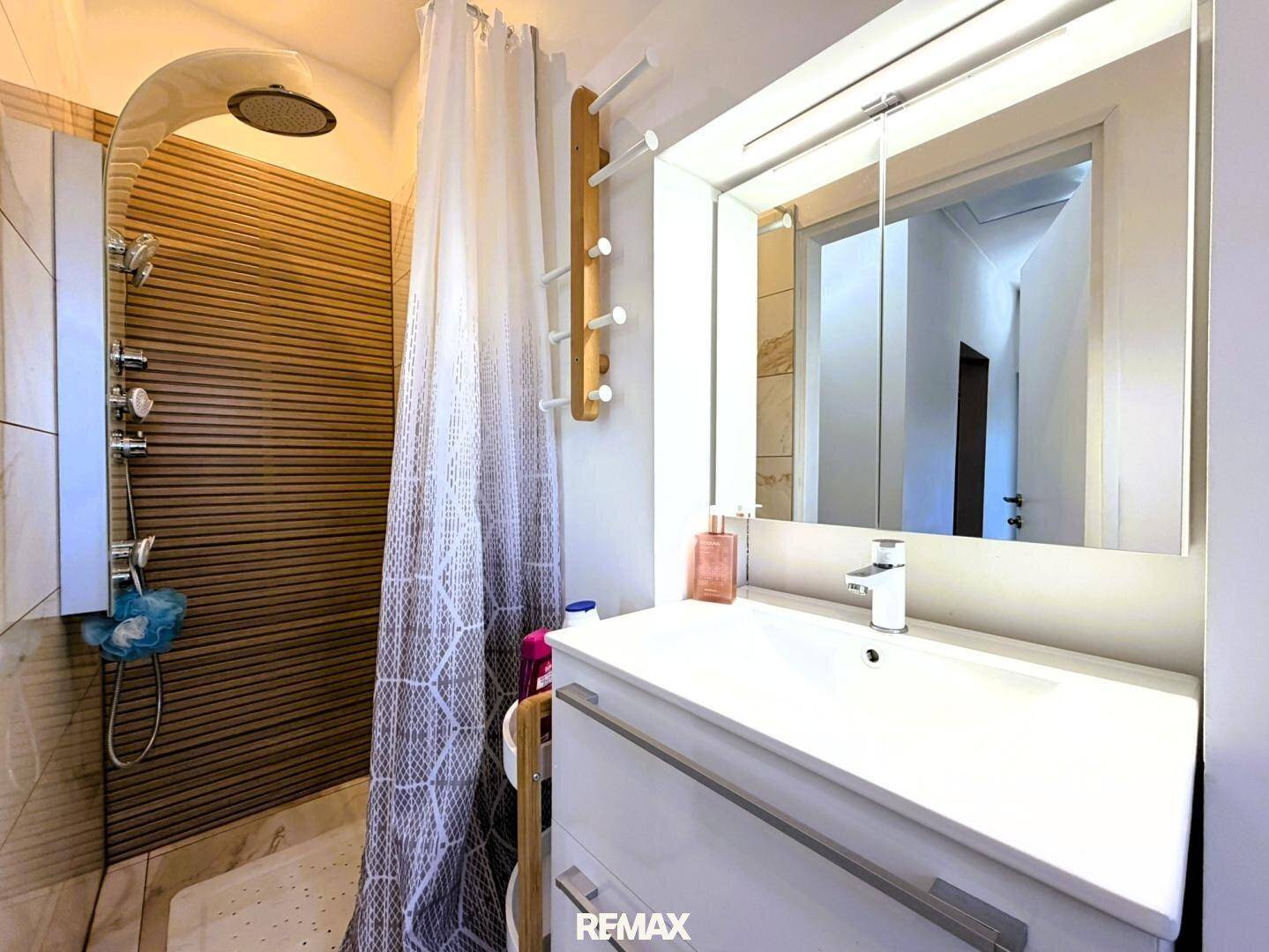 Modernes Badezimmer mit ebenerdiger Dusche, Einzelwaschbecken und Spiegelschrank.
