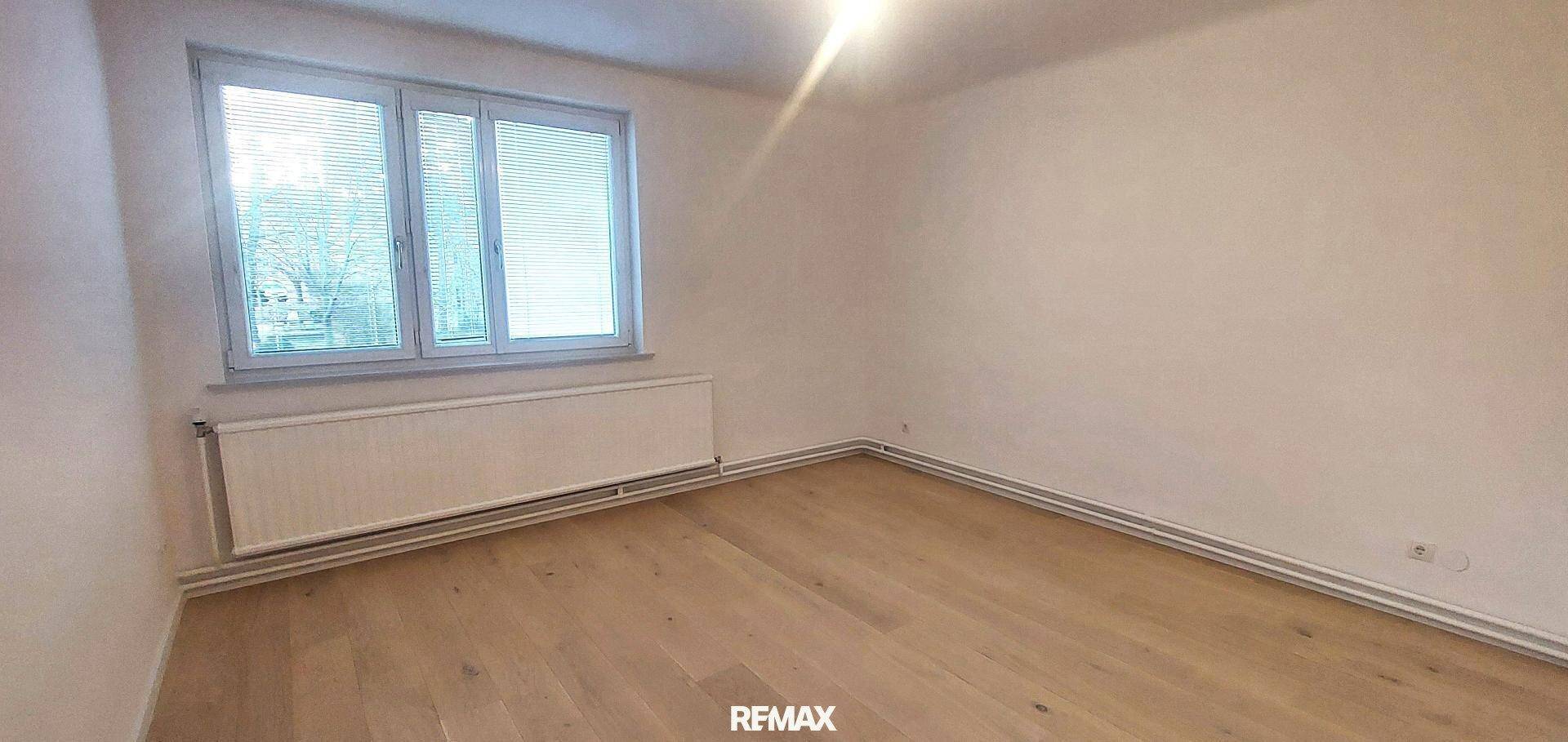 Ruhiges Zimmer mit Holzboden, weißen Wänden und Fenster mit Jalousien, geeignet als Schlafzimmer.