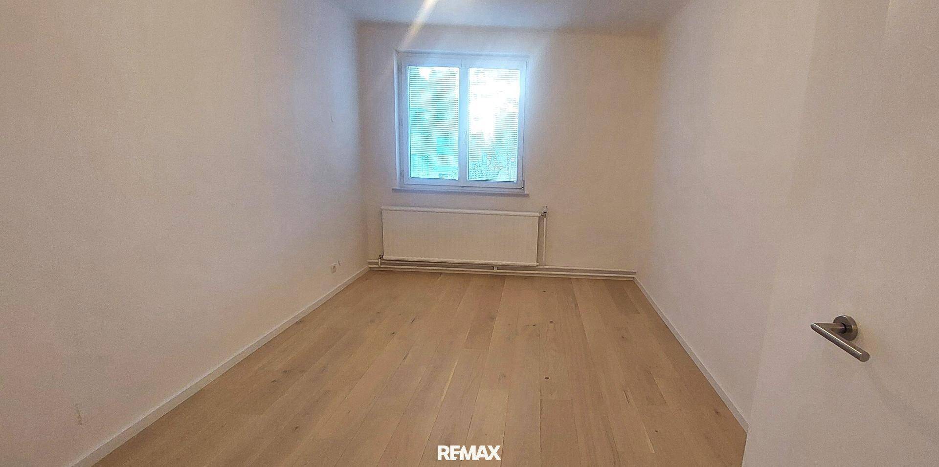 Kleines, helles Zimmer mit Holzboden und Fenster, ideal als Kinderzimmer oder Arbeitszimmer.
