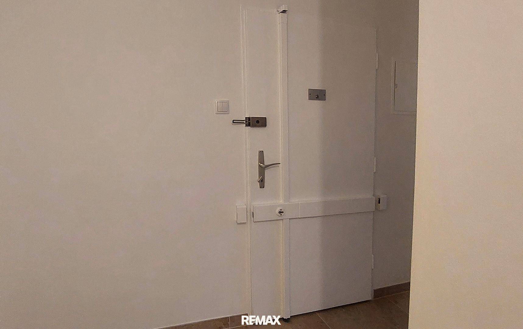 Robuste weiße Eingangstür mit mehreren Schlössern, die Sicherheit für die Wohnung bietet.