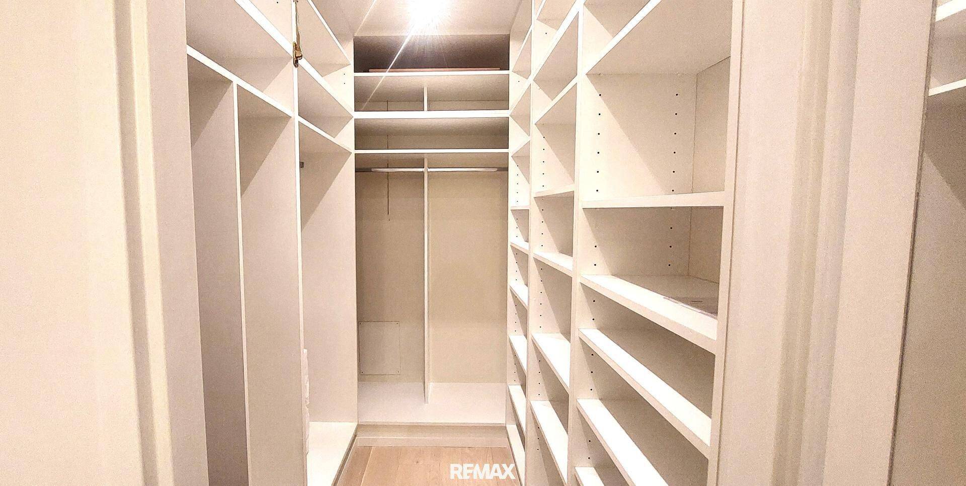 Geräumiger begehbarer Kleiderschrank mit vielen weißen Regalen und Stauraum.
