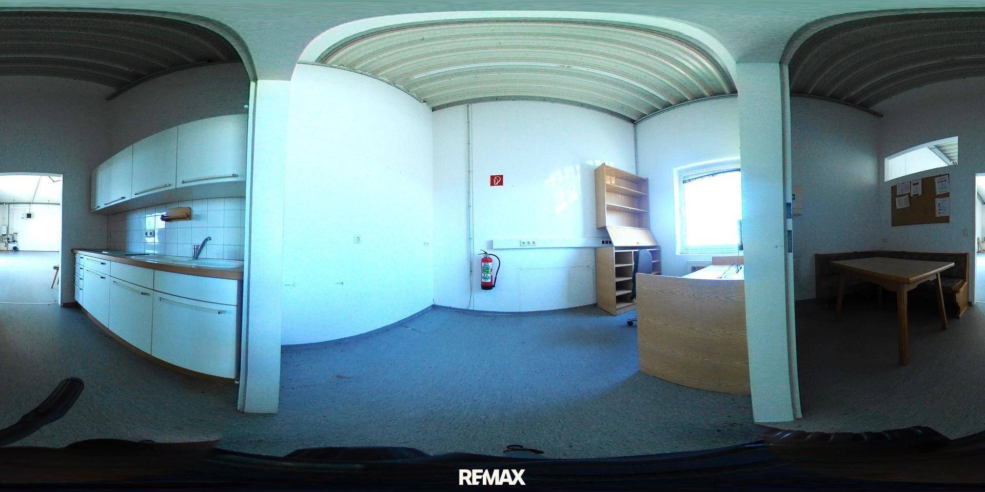 Panoramablick auf einen Innenraum mit einer kleinen Küchenzeile, einem Bürobereich und einem Esstisch.