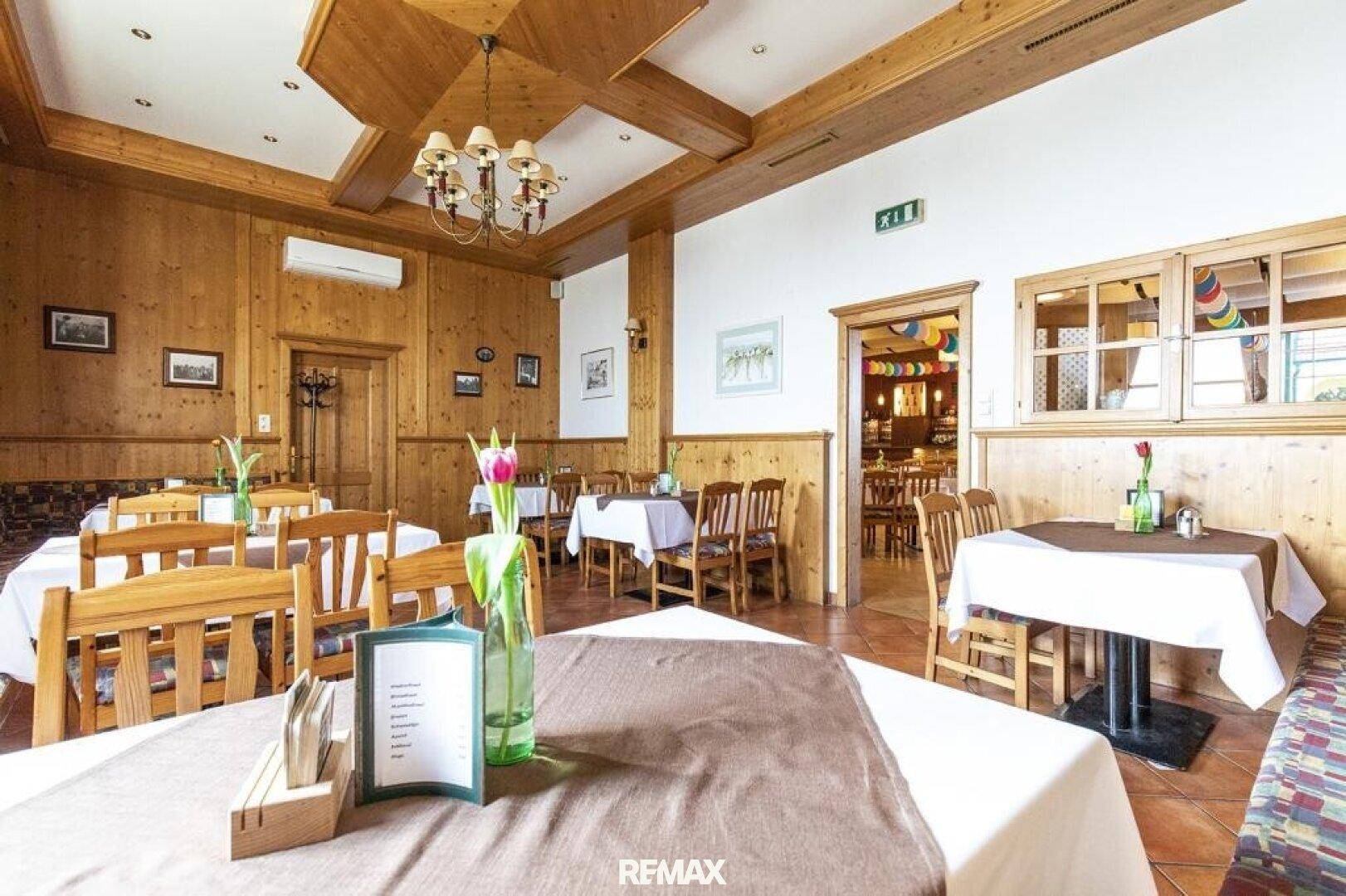 Gemütlicher Speisesaal mit Holzvertäfelung, traditionellen Tischen und Stühlen, durchflutet von Tageslicht.